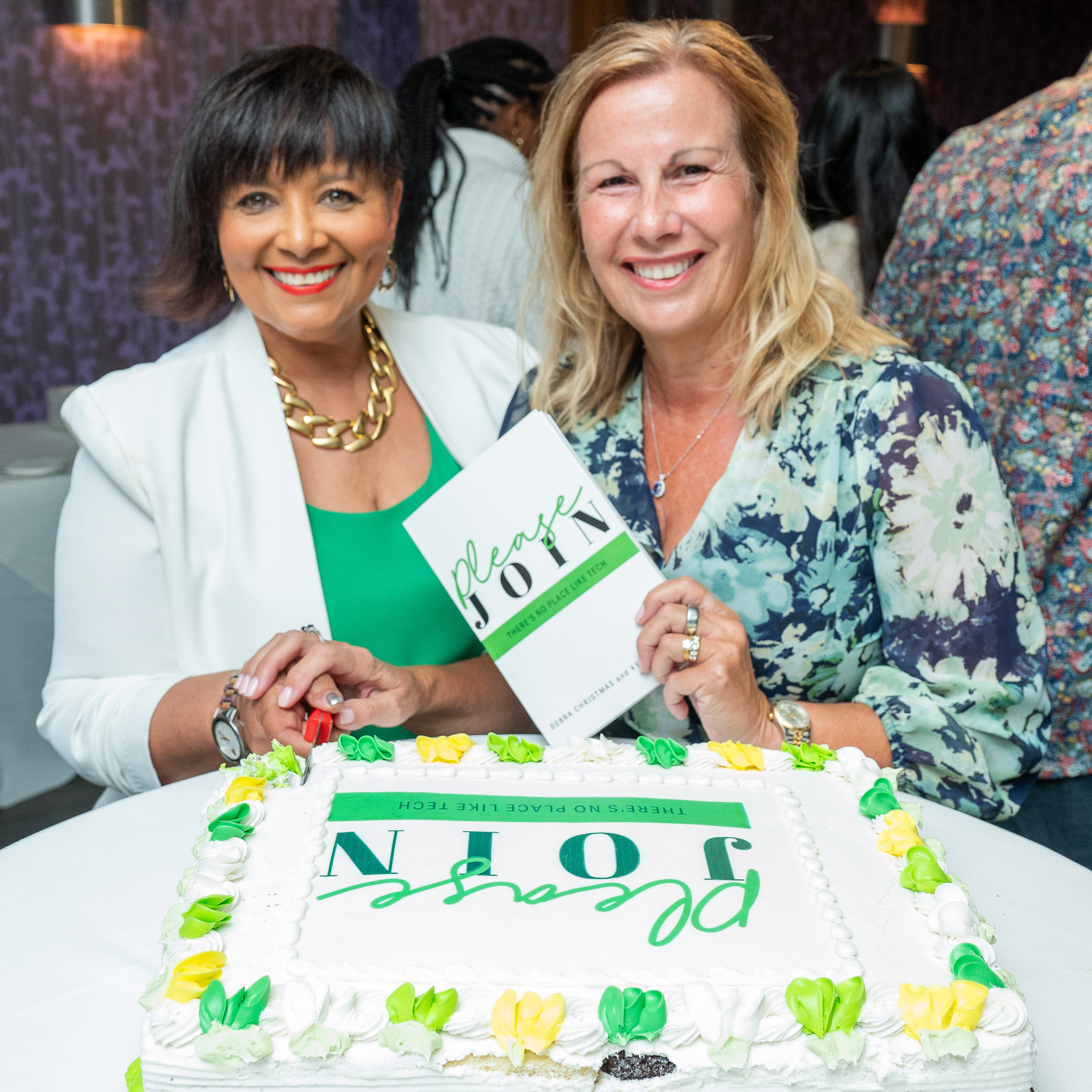 Two women celebrating a book launch with a cake