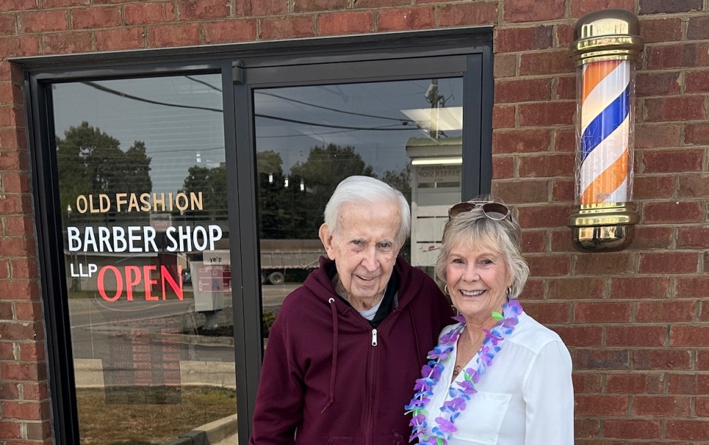 Man and Woman standing outside a barber shop