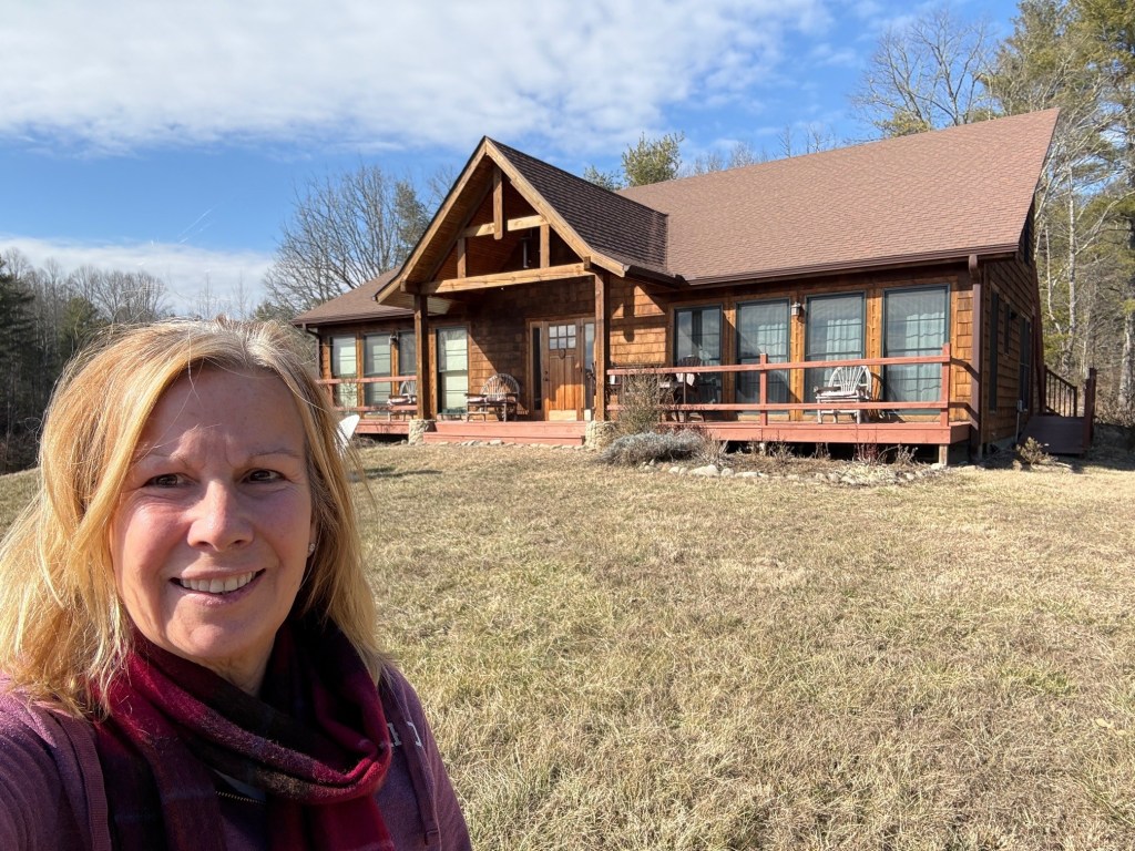 Kelley standing in front of a cottage in the mountains