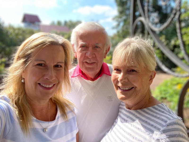 Kelley standing with her Mom and Dad outside