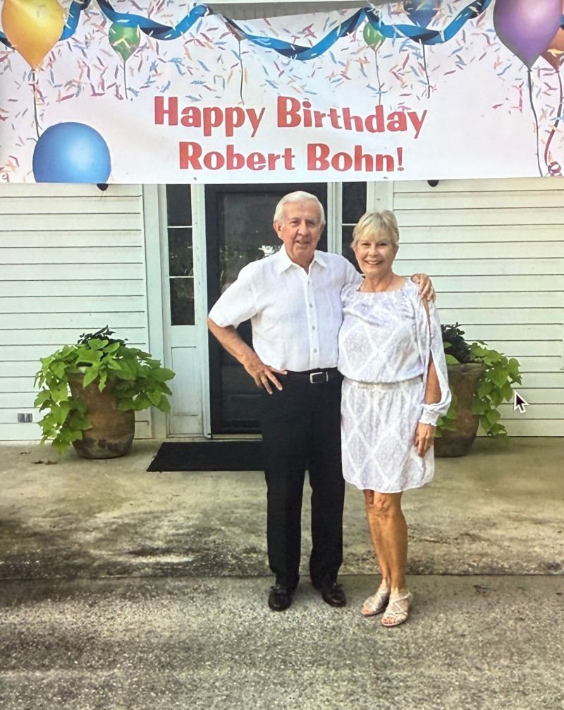Mom and Dad stand under a birthday banner