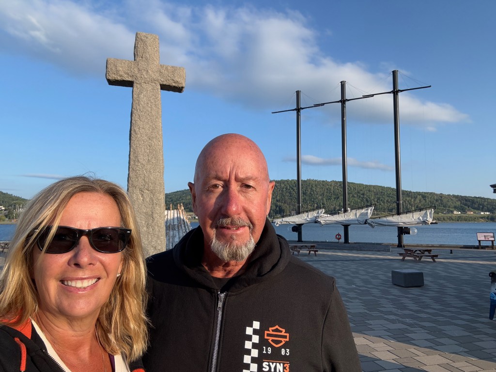 Les and Kelley at the waters edge in Gaspe with a large cross behind them