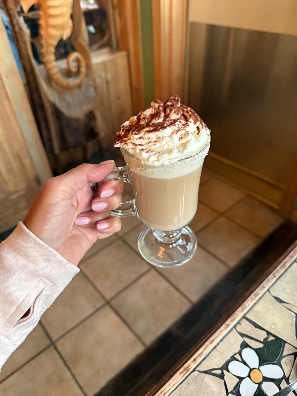 Kelley's hand holding a coffee with whipped cream on top