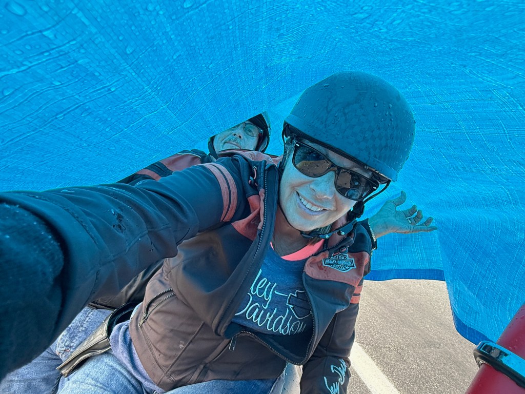 Les and Kelley under a blue tarp hiding from the rain