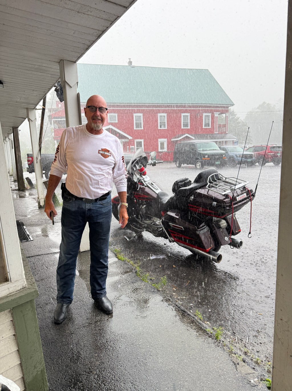 Les standing in the rain with the motorcycle behind him
