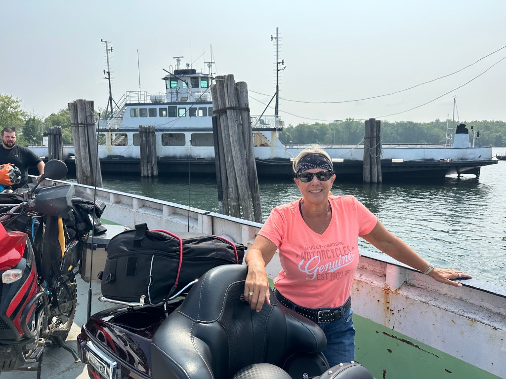 Kelley on a ferry standing beside their motorcycle